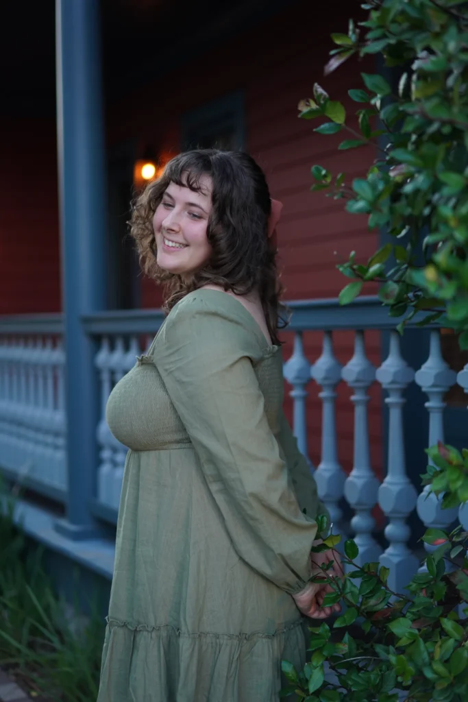 Author Julia Naus smiling in front of a cosy porch at dusk