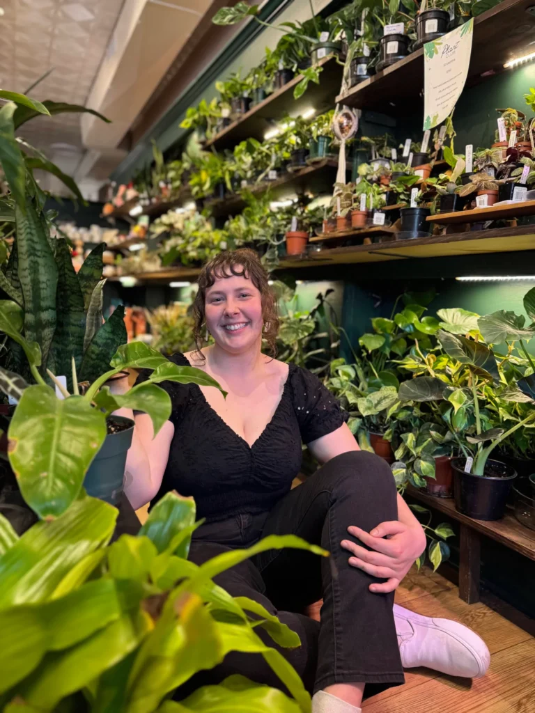 Julia sitting in a plant shop smiling at the camera